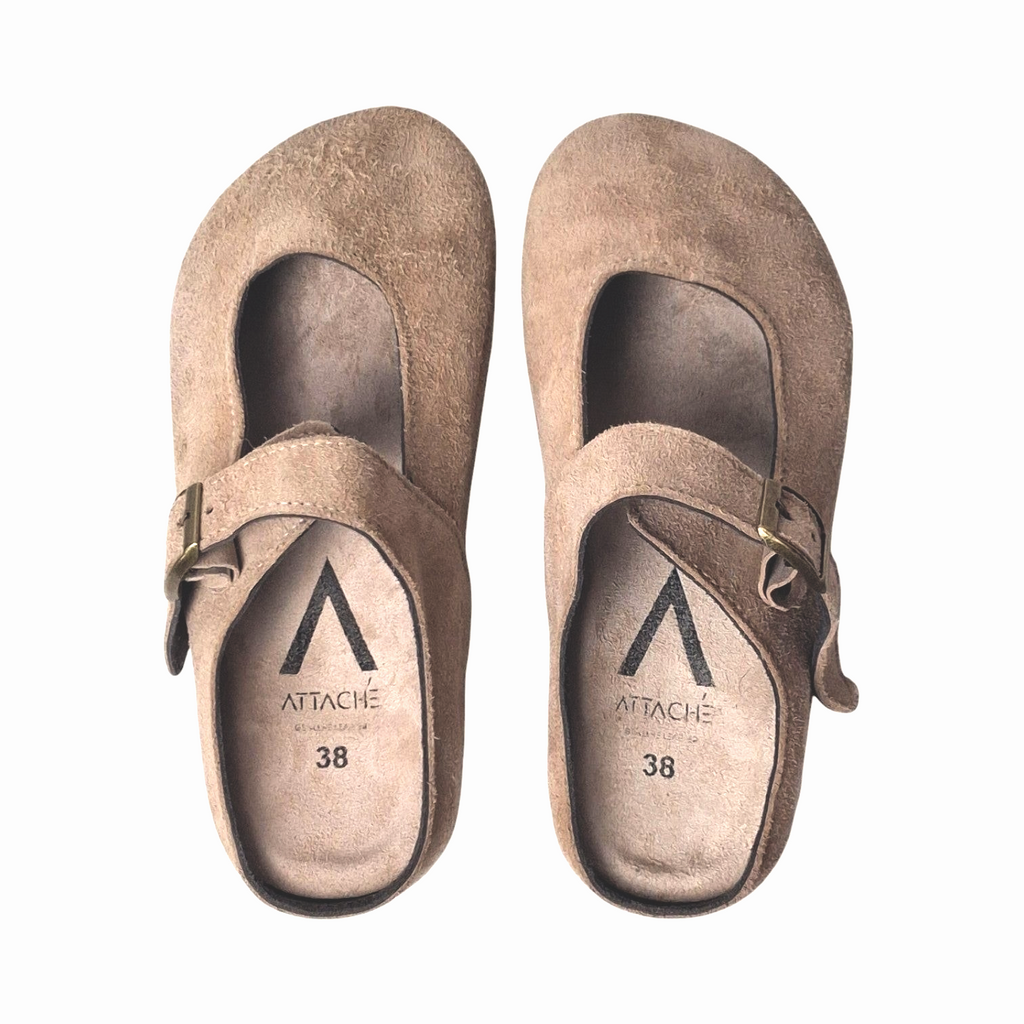 Attache Bags Merry Jane clogs in nude suede leather with an adjustable buckle strap and rounded toe profile.